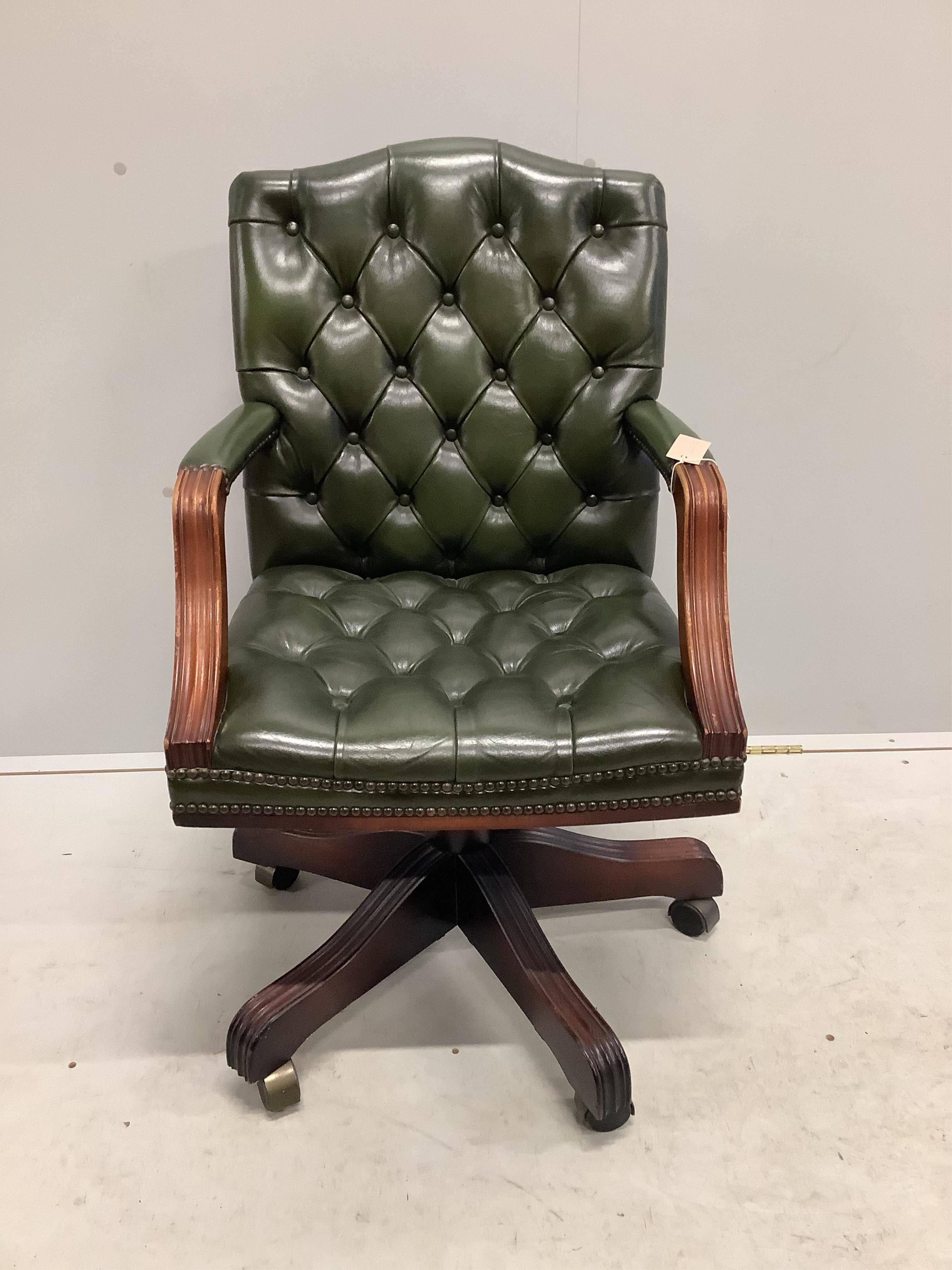 A reproduction mahogany and buttoned green leather swivel desk chair, width 56cm, depth 50cm, height 92cm. Condition - fair